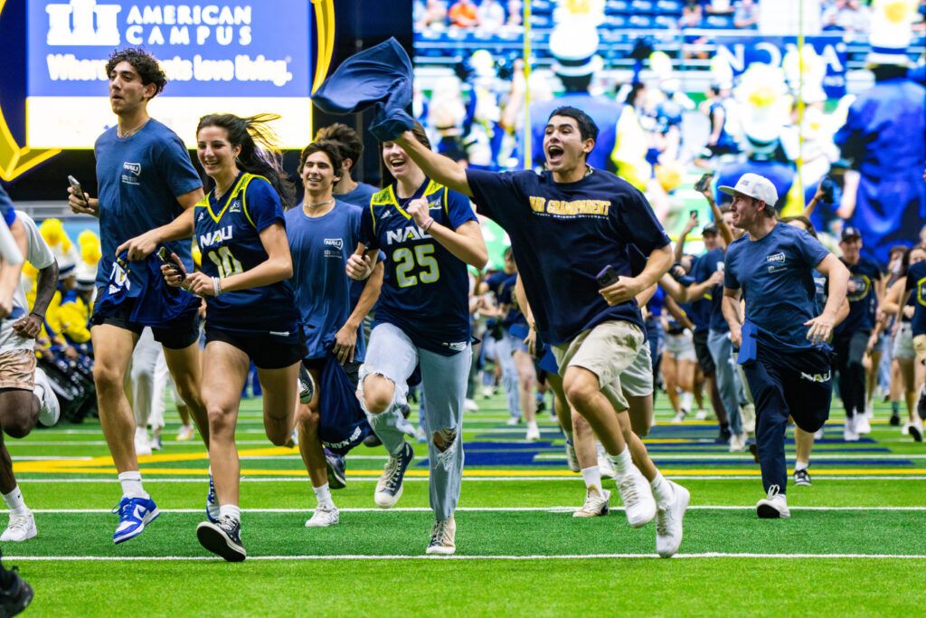Freshmen sporting NAU colors while running across NAU's football field for the "Running of the Freshmen" tradition.