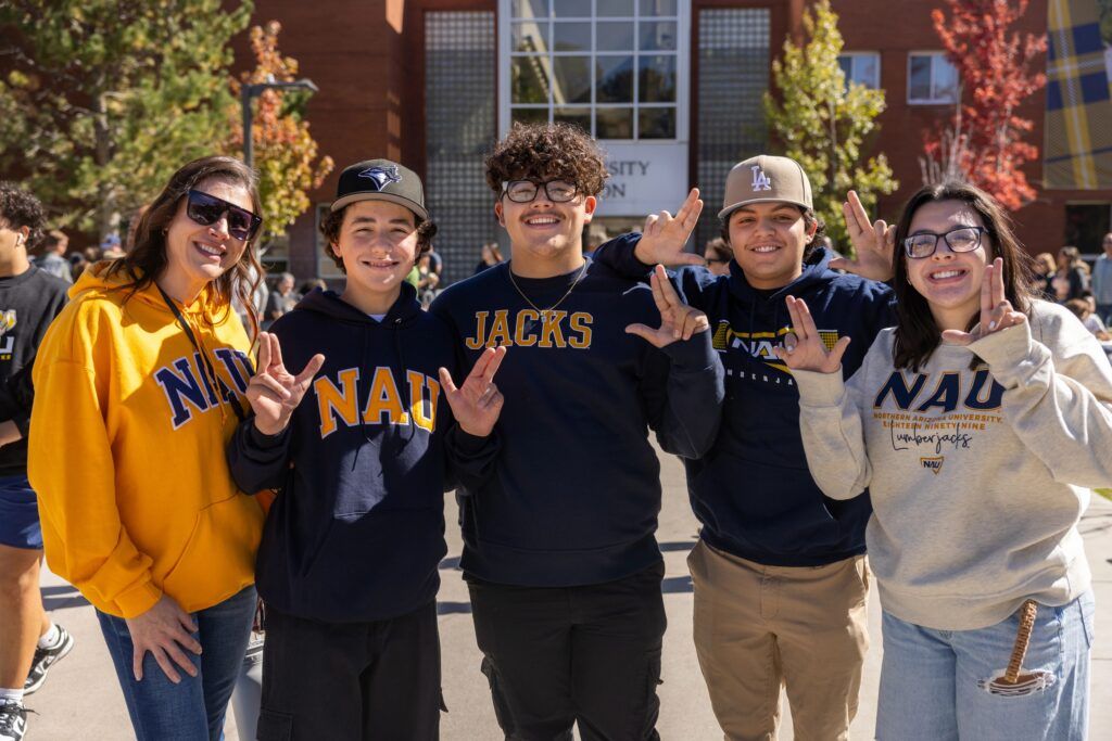 An N A U family throwing up the Lumberjack hand symbol during family weekend.