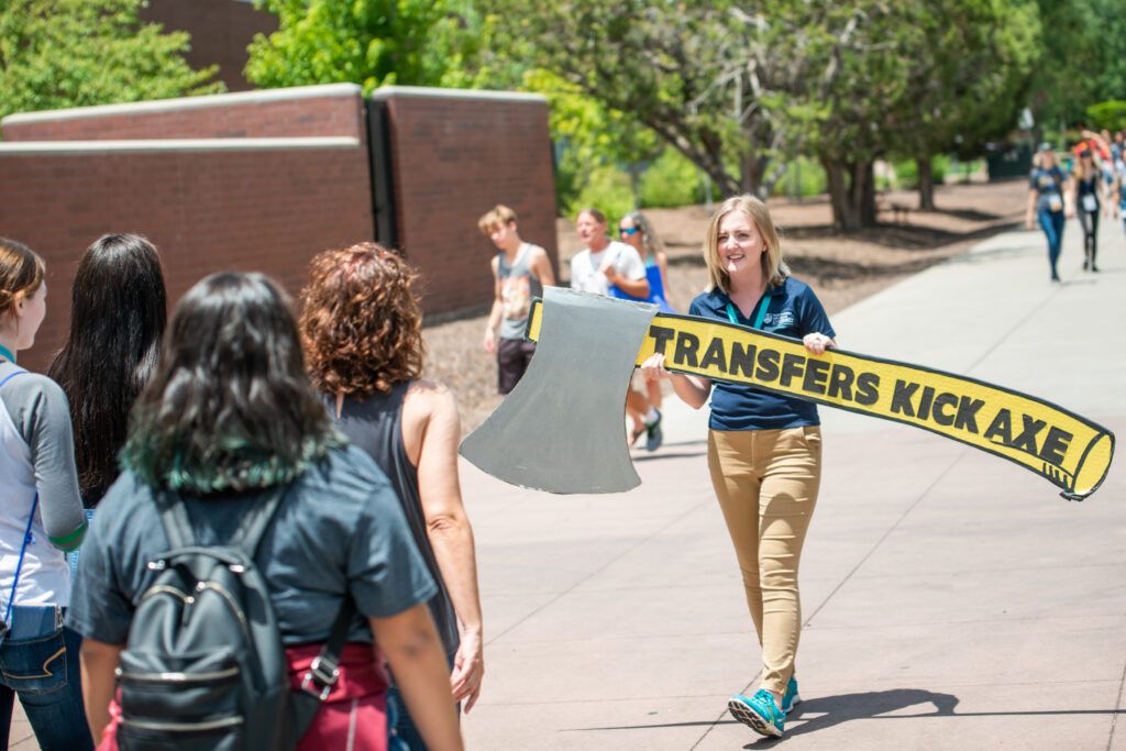N A U tour guide leads a group of visitors across campus, proudly holding the "Transfers Kick Axe" axe as they explore the university.