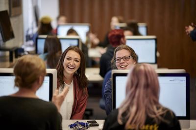 Students laughing and talking while at desktops.