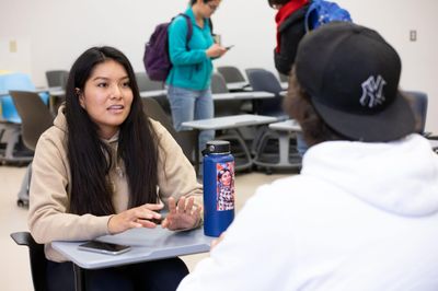Students talking to each other at desks.