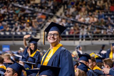 A smiling N A U student standing at commencement.