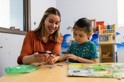 An N A U College of Education student happily works with a young student.