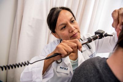 An N A U professor and doctor examines a patient.